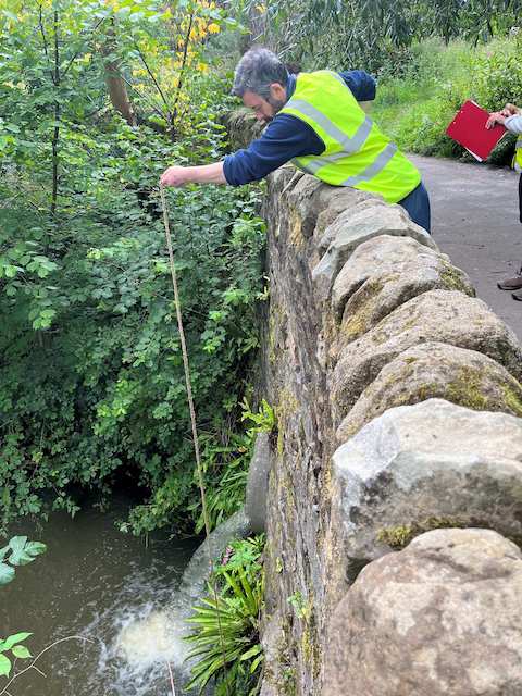 Hookstone Beck. Andy sampling from the stone footbridge. Water discoloured